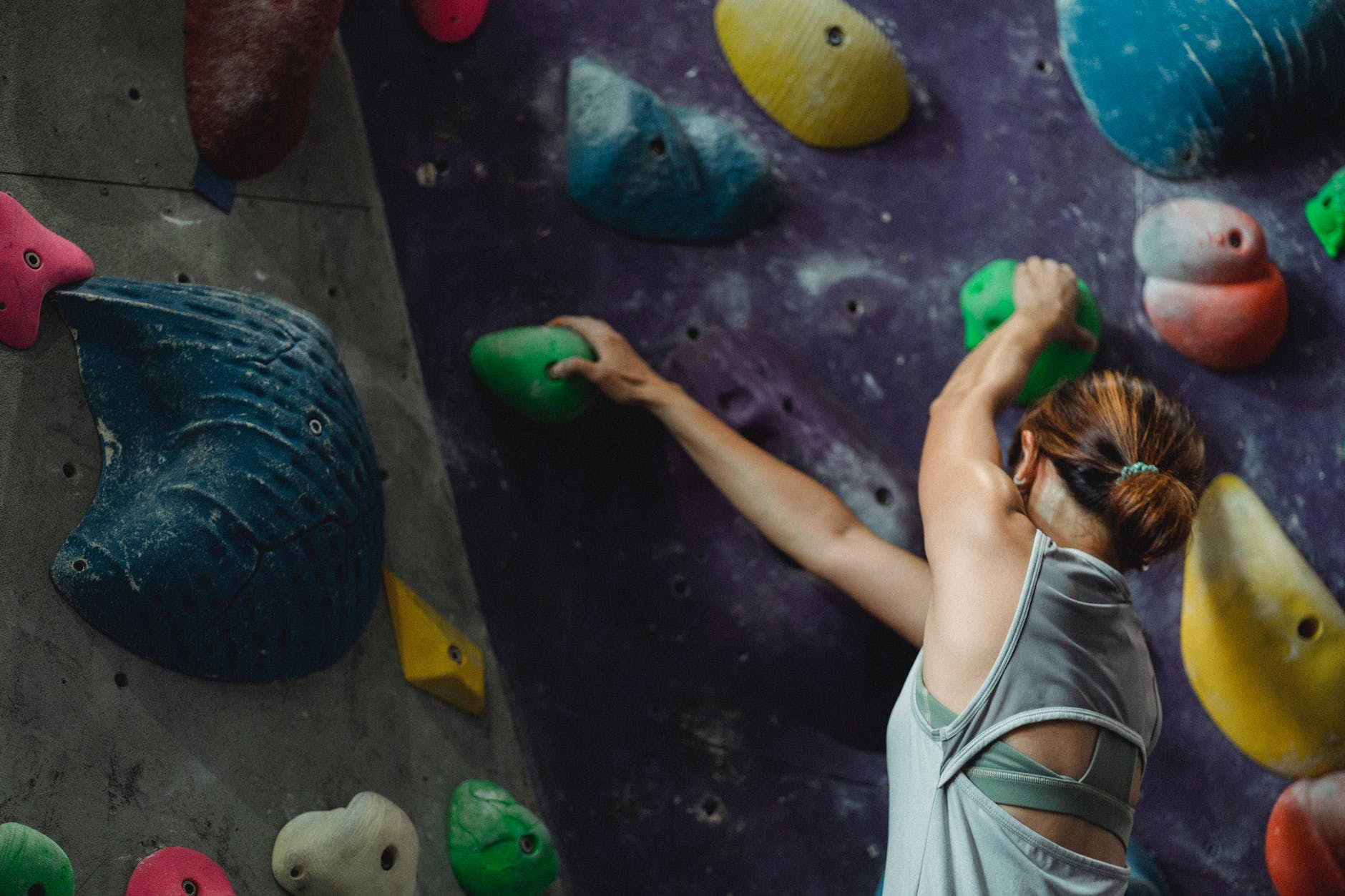 woman grabbing grips while ascending on climbing wall